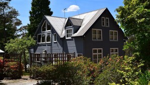 Uma casa de dois andares com fachada azul escura e telhado empena.