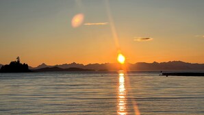 Un tramonto su acque calme con montagne sullo sfondo.