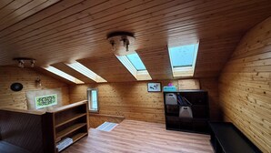 Una camera mansardata accogliente con pareti in legno e soffitti inclinati, dotata di lucernari, una panca integrata e un angolo cottura.