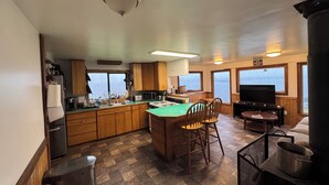 Una cucina compatta con mobili in legno, un'isola centrale con sedie, un fornello e una televisione.