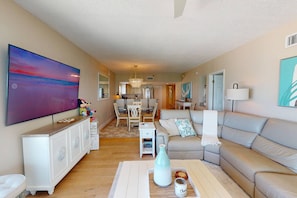 A living room with a large painting, a sofa, a coffee table, and a dining area.