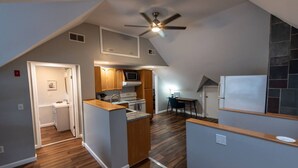 A modern kitchen with a central island, wooden cabinets, and a ceiling fan. - Cozy Loft steps from VT Downtown (Bennington)