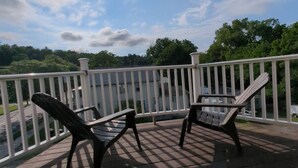 A deck with two chairs and a table, overlooking a body of water and trees. - Cozy Loft steps from VT Downtown (Bennington)