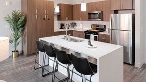 A modern kitchen with a central island, stainless steel appliances, and wooden cabinetry. - Convention Ctr Luxury 1BR Pool Gym Hot Tub (Salt Lake City)