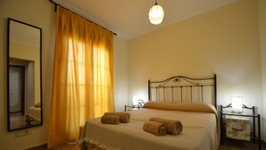 A neatly made bed with a headboard, a bedside table with a lamp, and a large mirror on the wall.