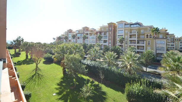 A multi-story hotel with balconies, surrounded by well-maintained lawns and palm trees.