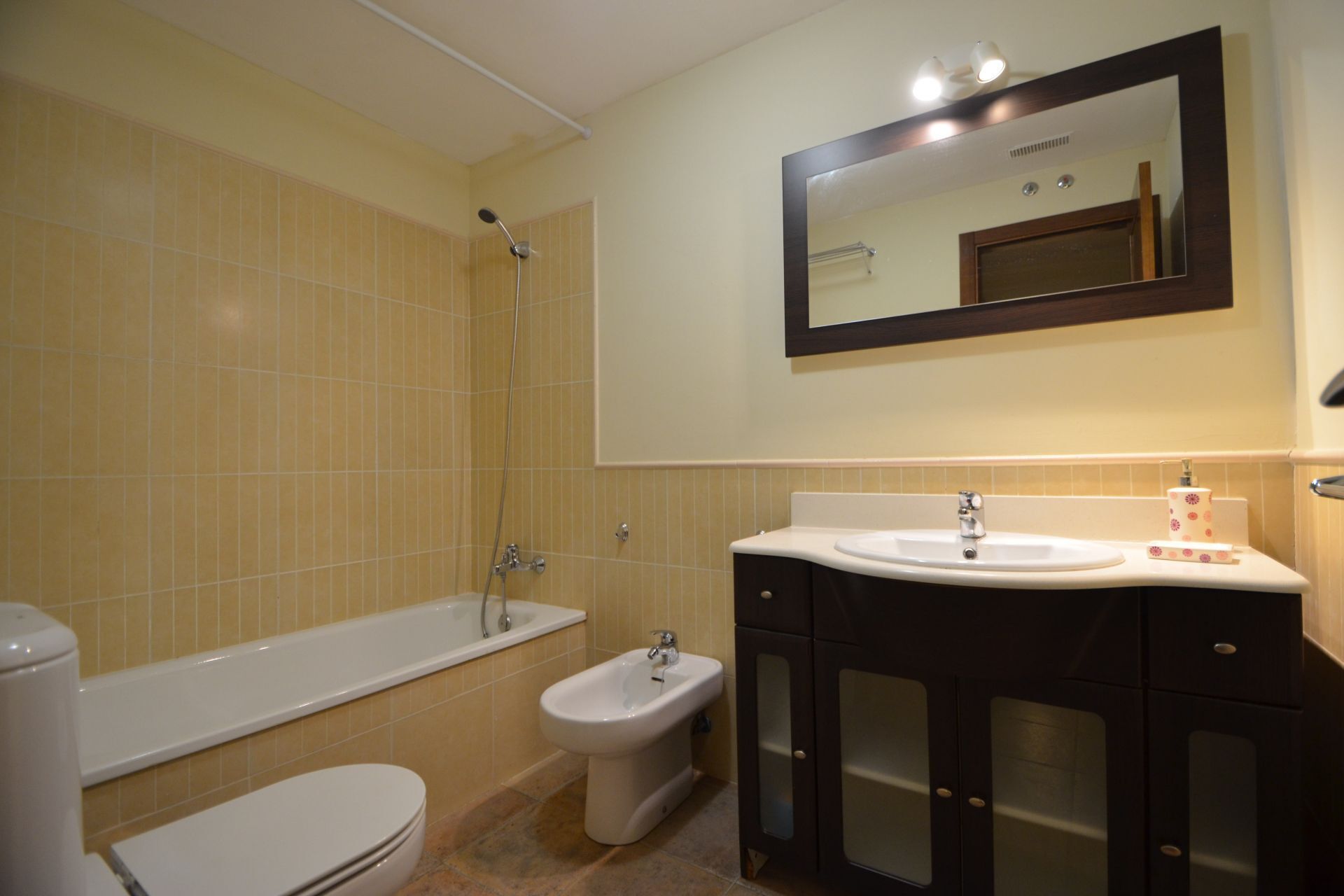Un baño con bañera, bidé, inodoro y lavamanos con espejo.