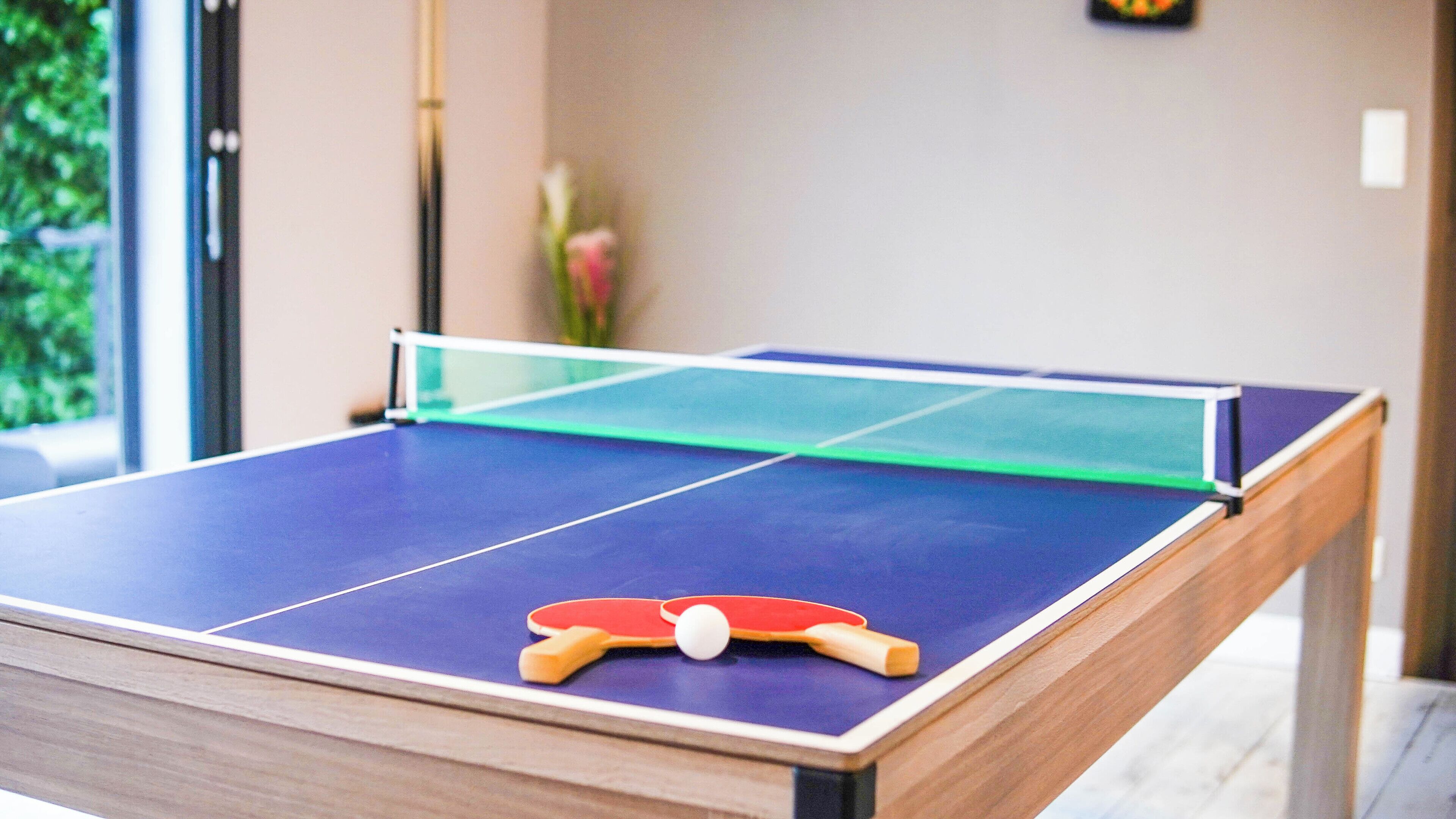 Une table de ping-pong avec un filet, une balle et des raquettes.