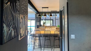 A modern kitchen with bar stools, a large black and gold artwork, and a sign reading "WELCOME". - Carcalove - Pool, Billiards & Jacuzzi - 10pax (Fontiès-d'Aude)
