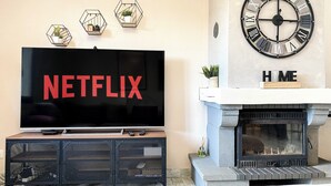A living room with a TV displaying the Netflix logo, a fireplace, and three hexagonal wall decorations. - Carcalove - Pool, Billiards & Jacuzzi - 10pax (Fontiès-d'Aude)