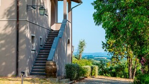 A building with a staircase leading to an upper level, a barrel, and a view of the countryside.