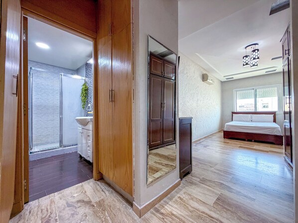 Une chambre à coucher comprenant un lit, une armoire et une salle de bain avec un lavabo et une douche.