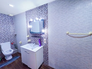 A bathroom with a white sink, mirror, and toilet.