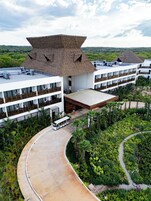 Un resort con varias edificaciones, un área exterior techada y un camino sinuoso rodeado de abundante vegetación.