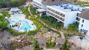A resort with a central pool, multiple buildings with thatched roofs, and a surrounding tropical garden. - Hotel Mundo Maya Nuevo Uxmal (Santa Elena)