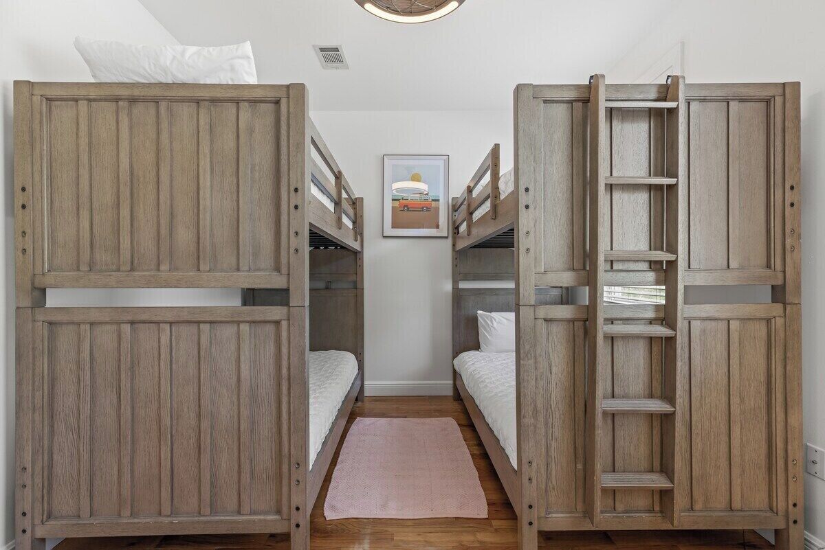 A bunk bed room with a ladder, a small rug, and a framed picture on the wall.