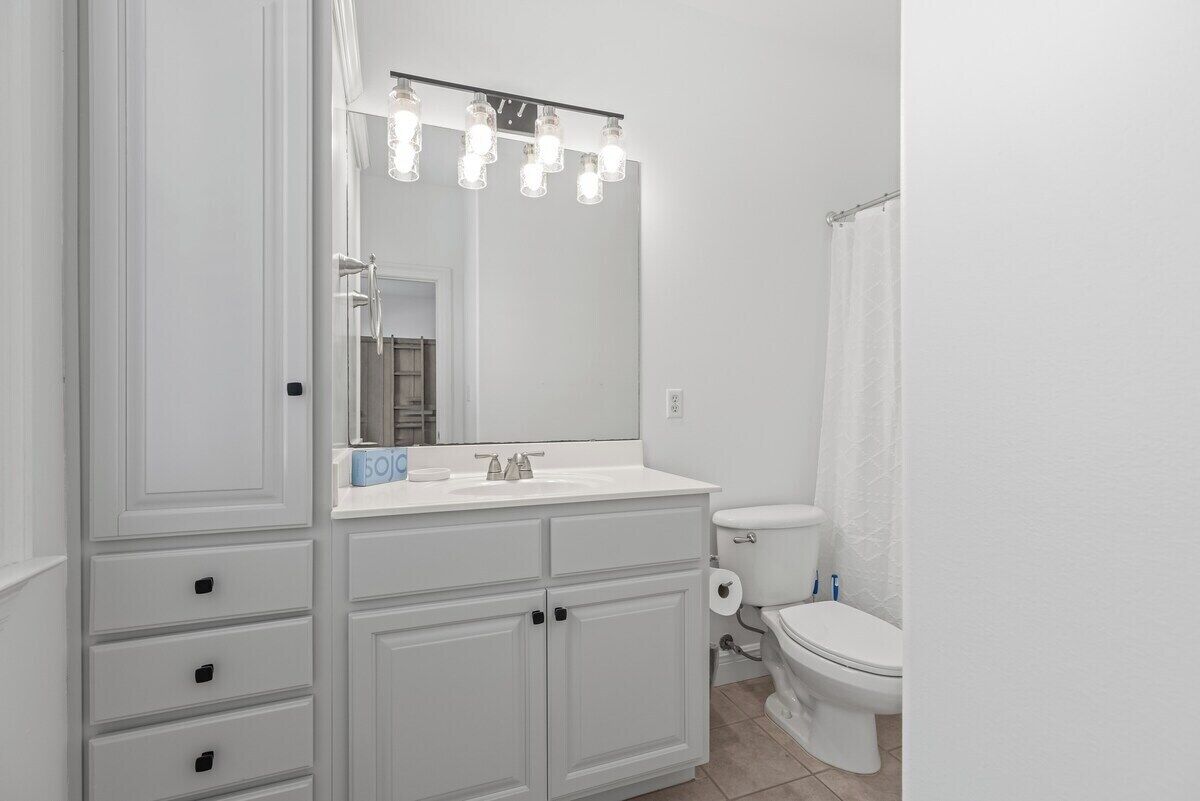 Une salle de bain avec un meuble-lavabo blanc, un grand miroir et un rideau de douche.