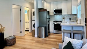 Una cocina moderna con armarios blancos, electrodomésticos de acero inoxidable y suelo de madera.