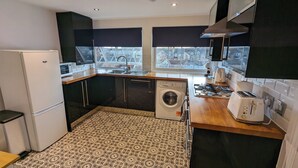 Une cuisine de taille réduite équipée d’un lave-linge, d’une cuisinière et d’un évier.