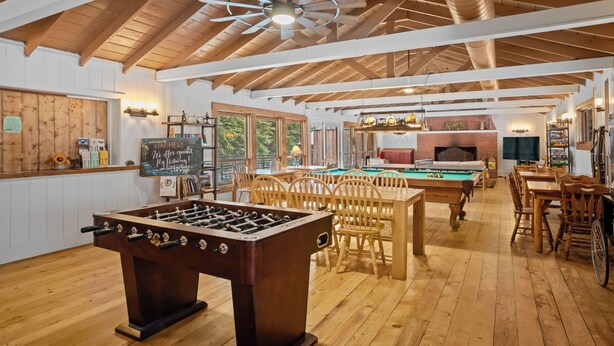 A spacious indoor area with a foosball table, pool table, and wooden furniture.