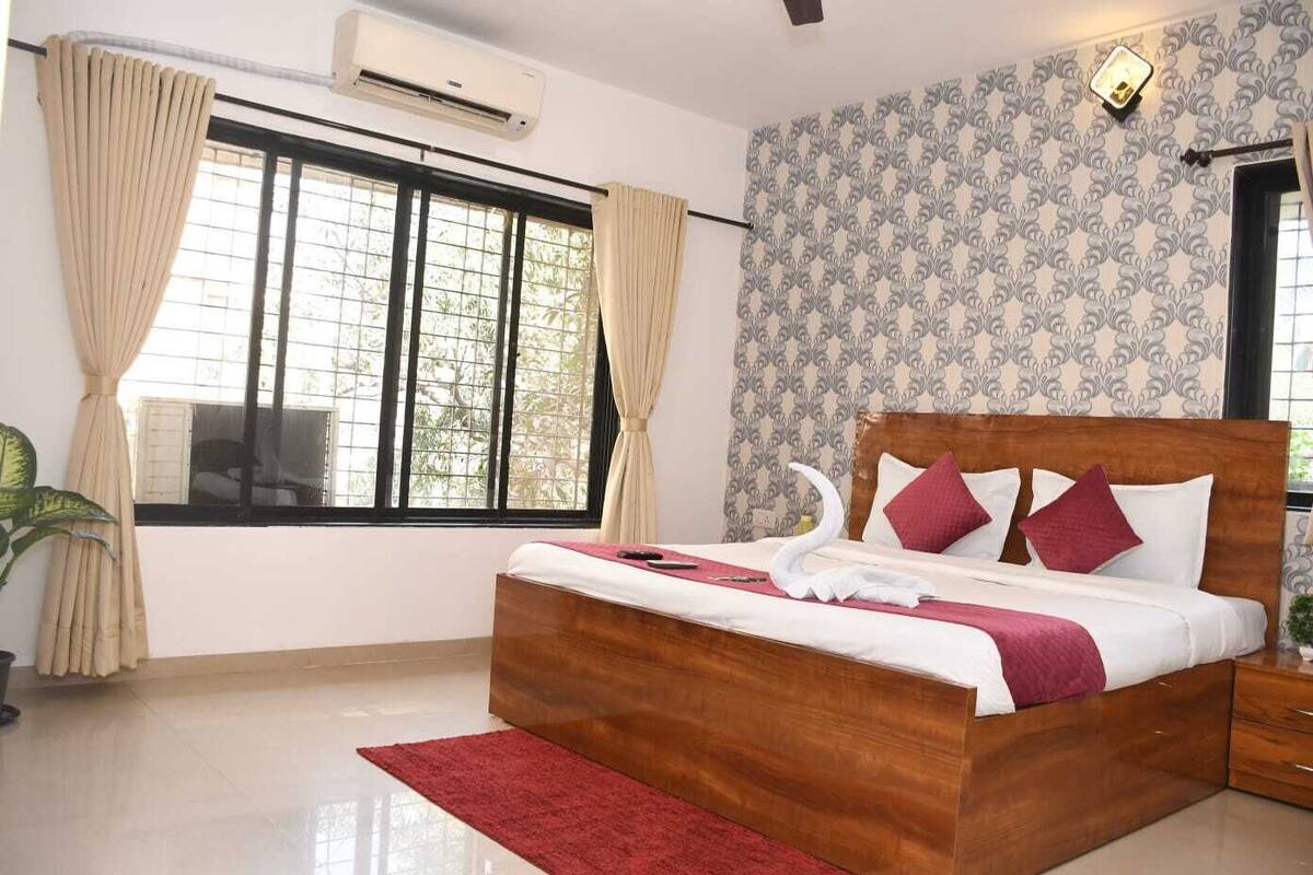 A bedroom with a wooden bed, a red rug, a window with curtains, and a patterned wall.