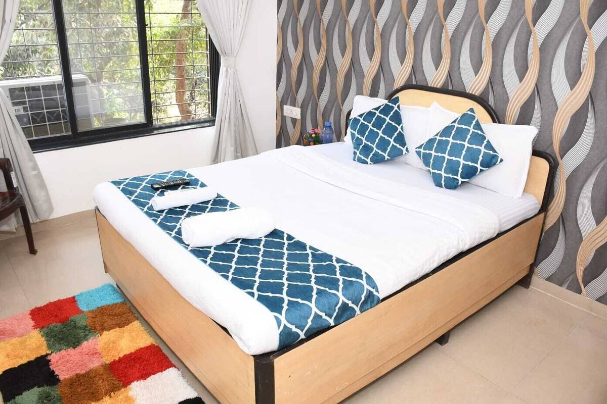 A bed with a blue and white patterned bedspread, two matching pillows, and a colorful rug.