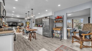 A spacious kitchen with a large island, stainless steel appliances, and a dining area with wooden chairs.