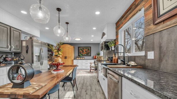 A modern kitchen with wooden cabinets, a marble countertop, and pendant lighting.