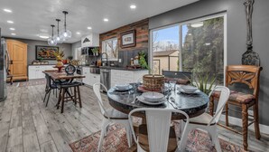 A modern kitchen with a dining area, featuring a large island, white cabinetry, and a view of the outdoors.