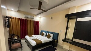 Une chambre d’hôtel équipée d’un lit, d’un bureau, d’une chaise, d’une télévision et d’un ventilateur de plafond.