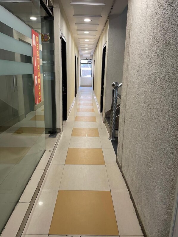 A corridor with a checkered floor pattern, glass doors, and a sign indicating a restaurant.