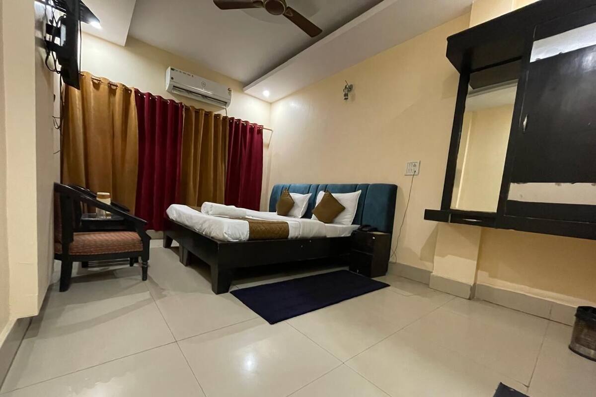 A bedroom with a bed, a chair, a desk, and a wardrobe.