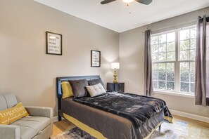 A bedroom with a bed, a nightstand, a lamp, a window with curtains, and a ceiling fan. - Tee Off in Augusta: Masters Retreat w/ Patio (Graniteville)