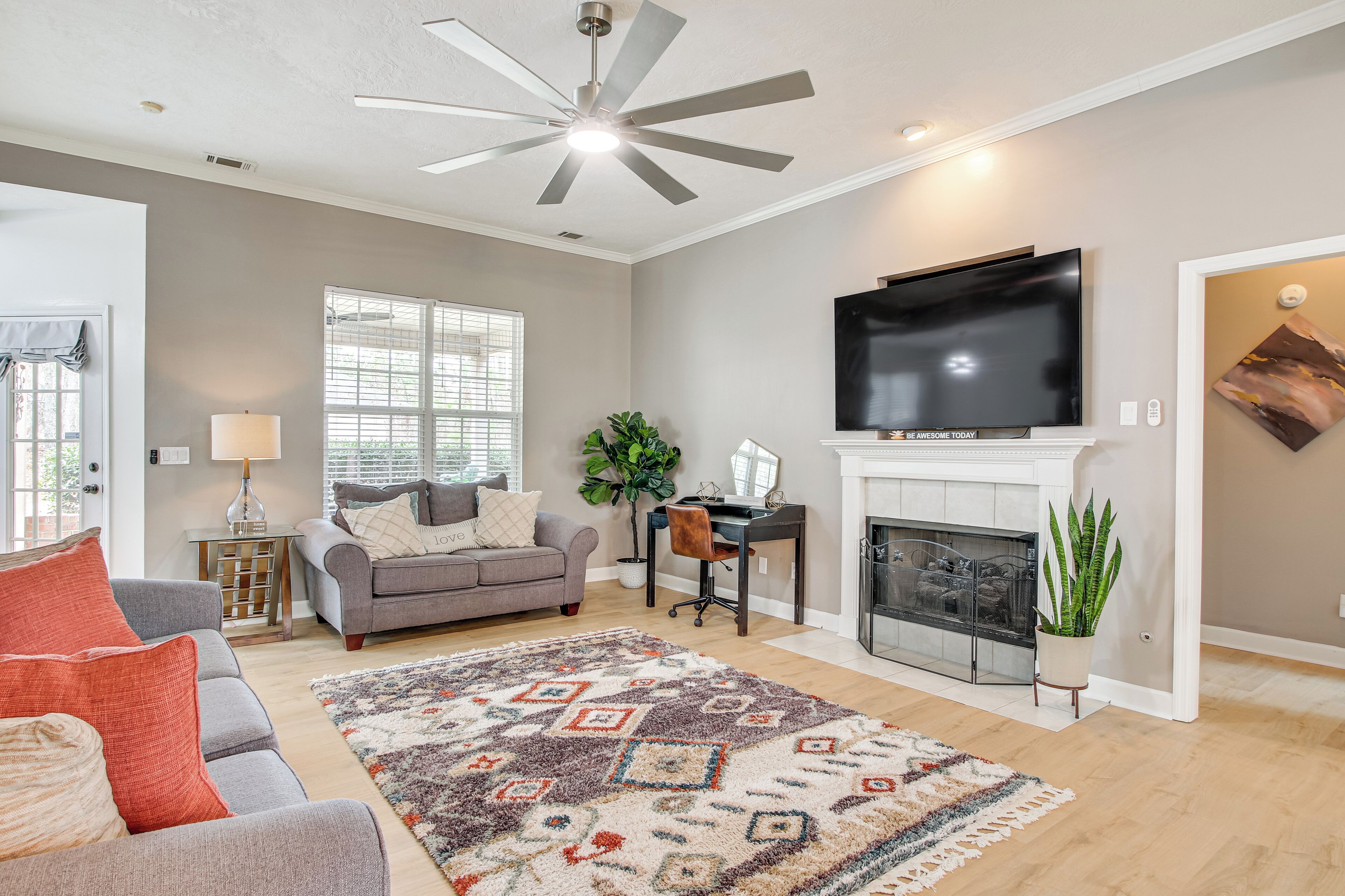Una sala de estar con chimenea, televisor y ventilador de techo.