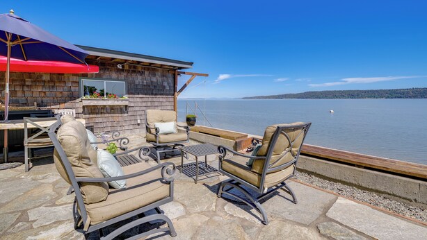 Un patio con mobiliario exterior, una zona de barbacoa y vistas al agua.