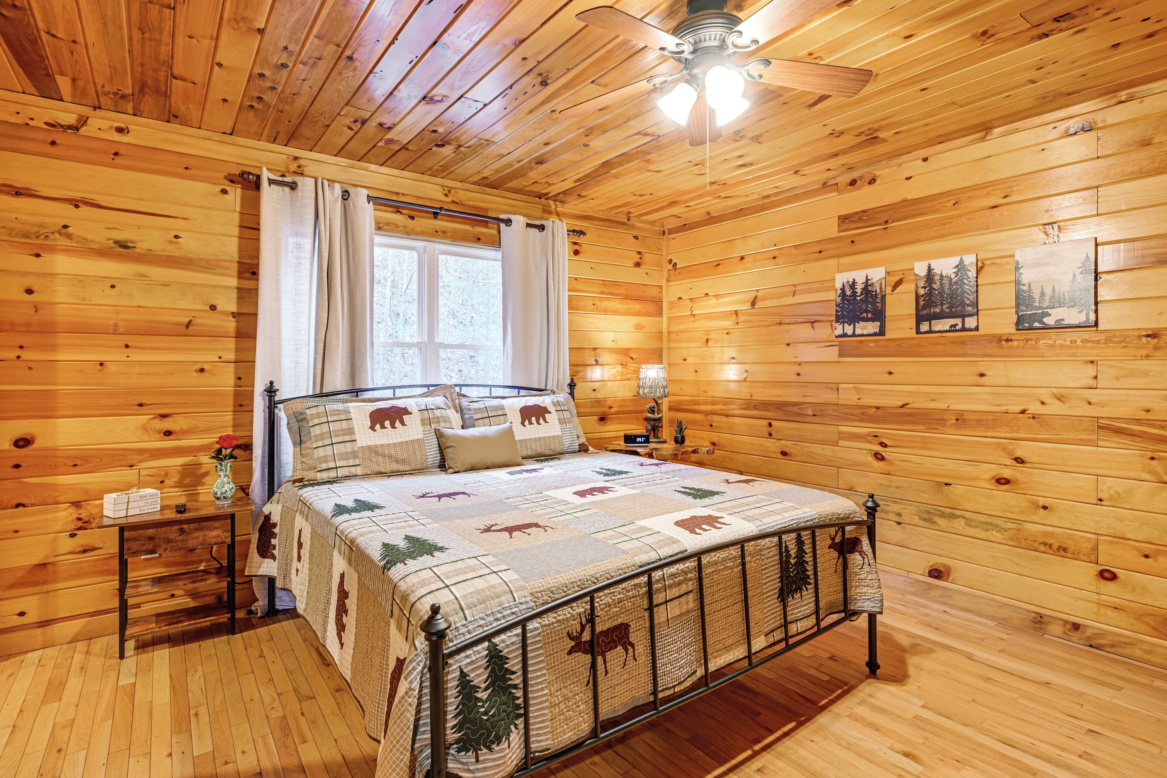 Ein Schlafzimmer einer Holzhütte mit Bett, Nachttisch und Wandbildern.