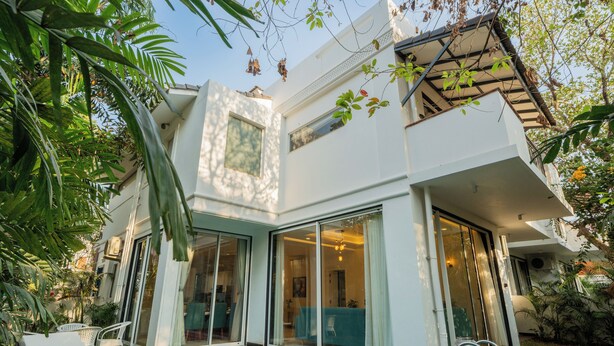 A modern house with a swimming pool, large glass doors, and a balcony. - ELIVAAS Laguna Camellia | Luxe 4 BHK Villa Near Popular Beaches with Private Pool (Anjuna)