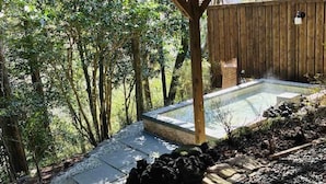 An outdoor hot tub area with a wooden deck, stone pathway, and surrounding trees. - HAKONE saryo KINTOKI (Hakone)