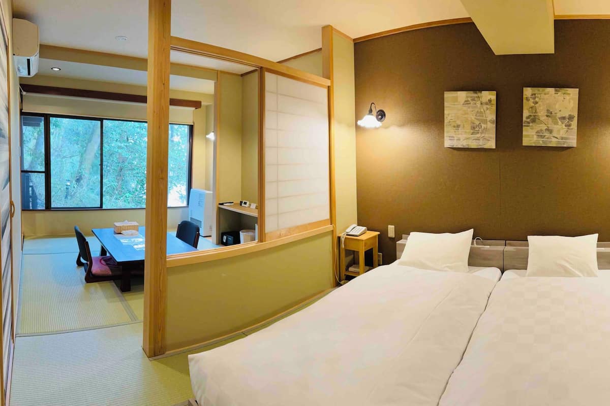A hotel room with a bed, bedside tables, a desk with a chair, a mirror, and artwork on the wall.