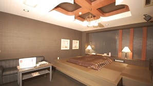 A modern hotel room with a large bed, a sitting area with a sofa, and a desk.