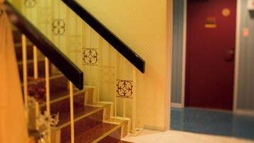 Una escalera con barandillas de vidrio y una puerta roja al fondo.