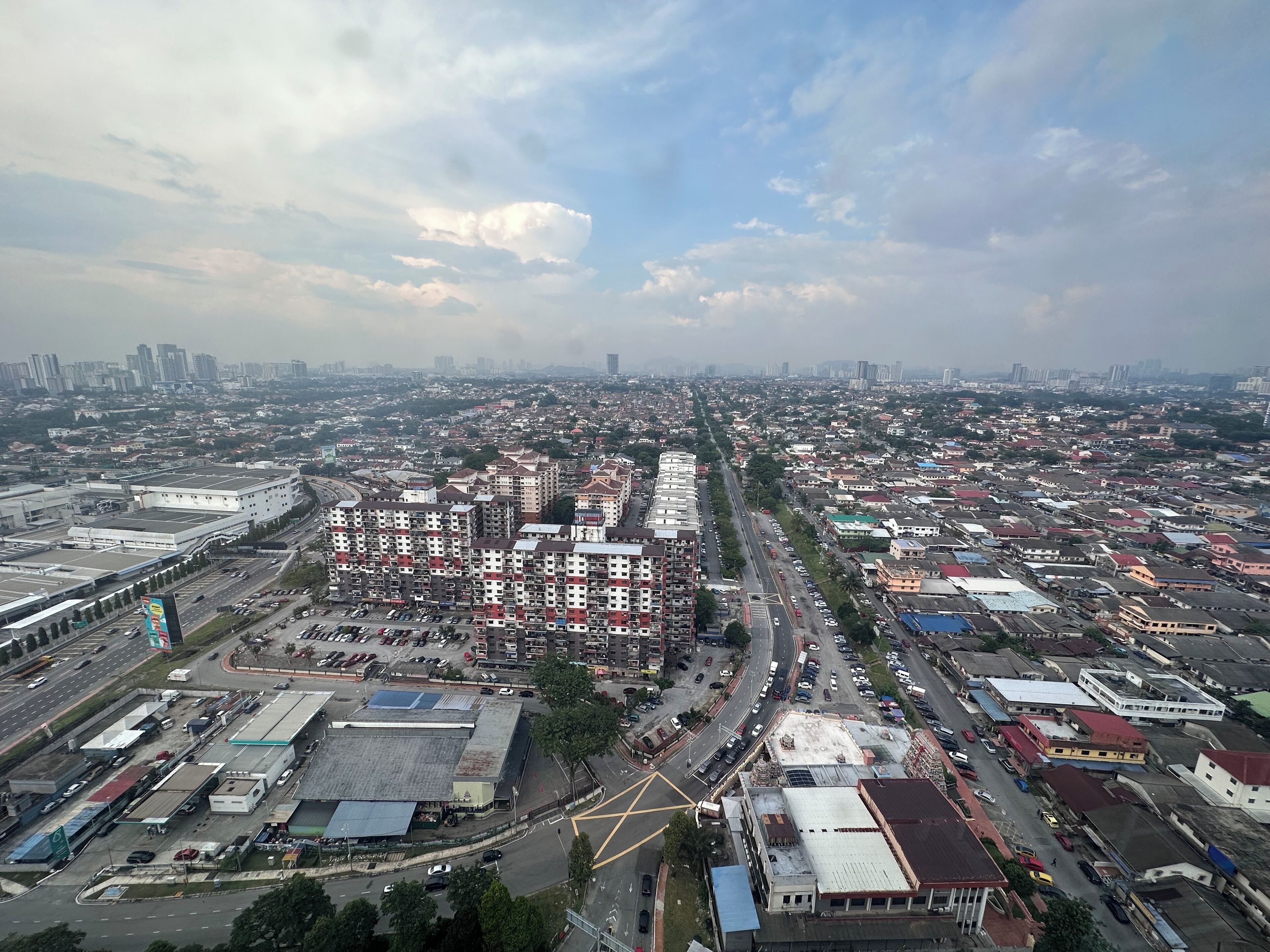 A cityscape with a prominent multi-story building with a red roof, surrounded by various other buildings and roads.