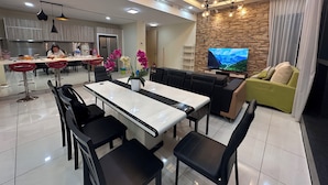 A modern living room with a TV, sofa, and dining area. - Skyline Luxe 4BR Retreat with En-suites (Petaling Jaya)