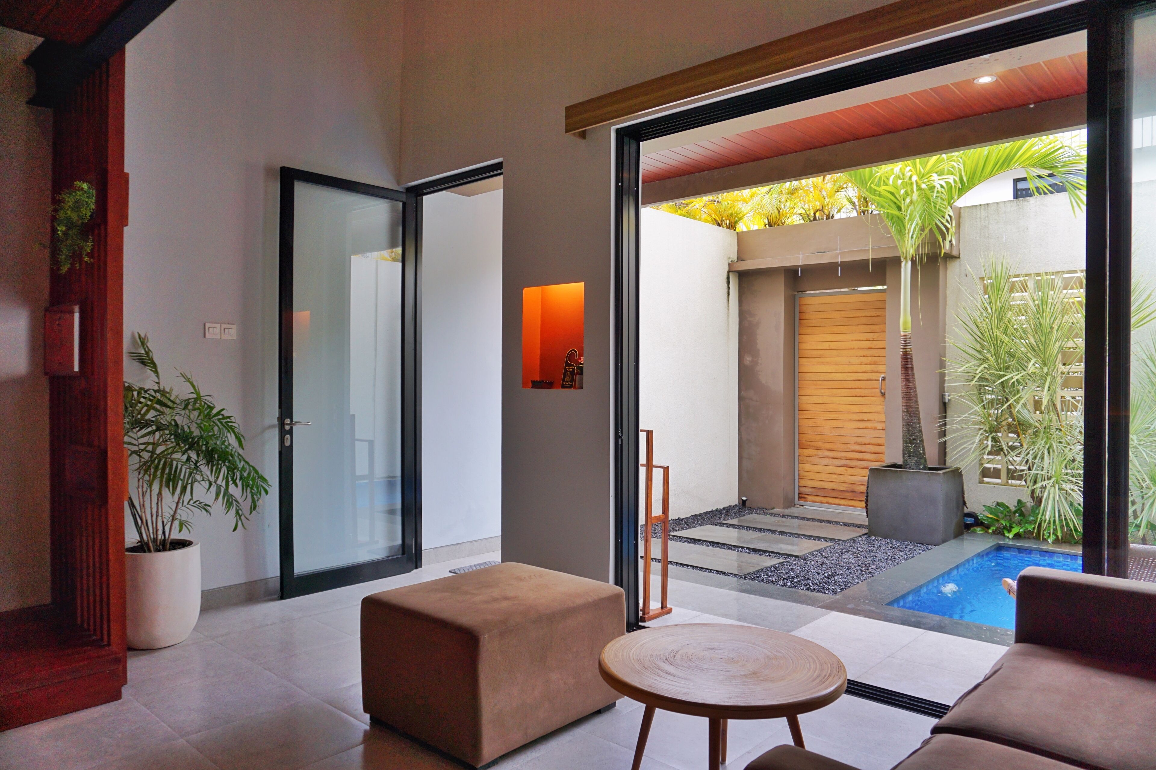 Un intérieur moderne avec une porte vitrée donnant sur une cour intérieure agrémentée d’une piscine et de plantes.