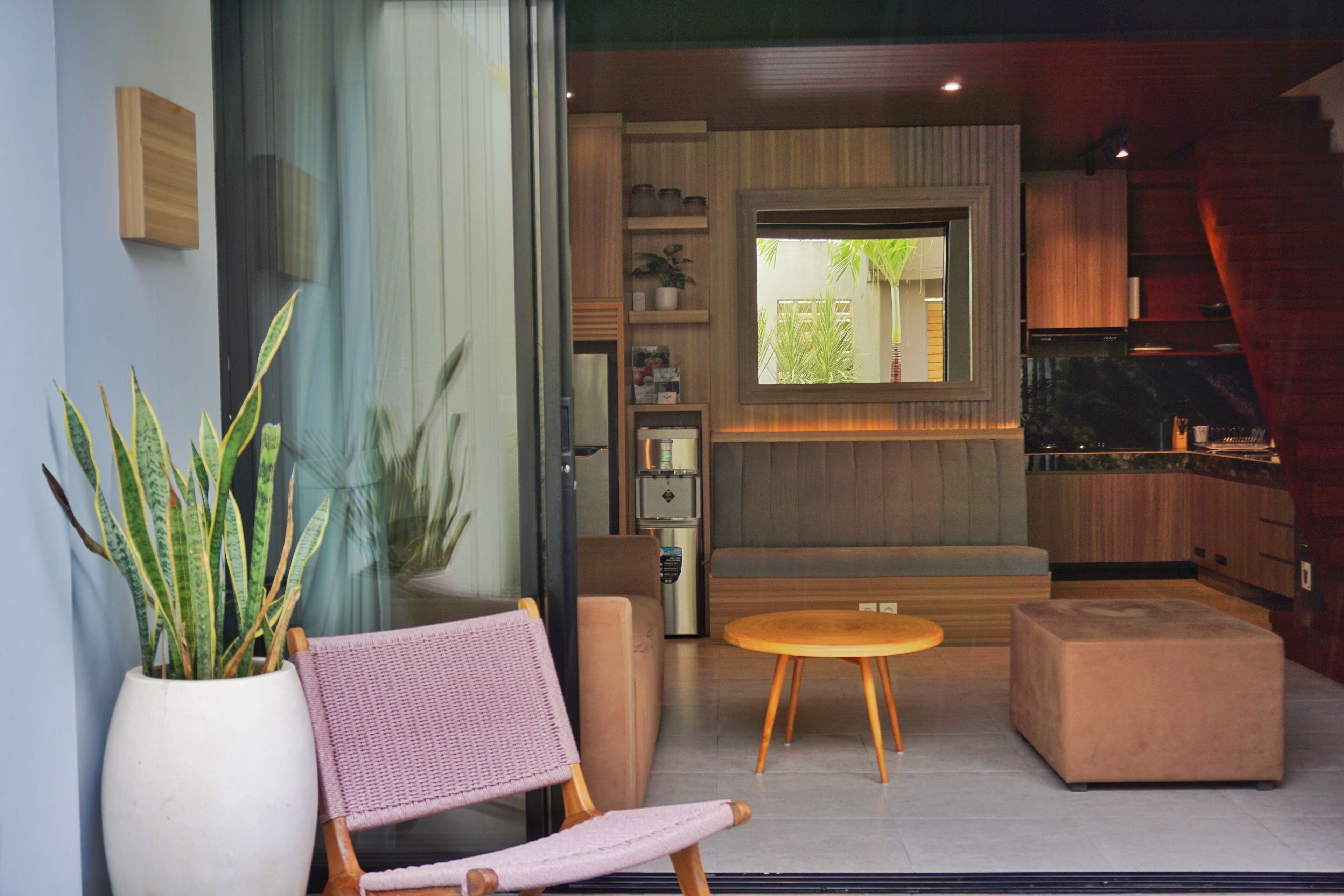 A modern living room with a sofa, a chair, a small table, and a potted plant.