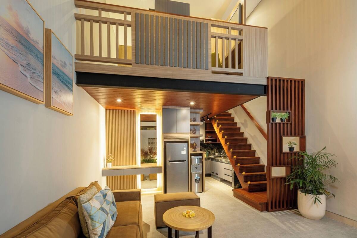 Un apartamento moderno estilo loft con cocina, comedor y una escalera que sube a un nivel superior.