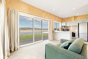 Una cocina moderna con vistas al campo, una puerta corrediza al exterior y un sofá verde en la sala de estar.