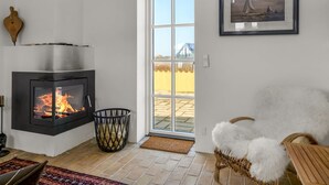 Ein modernes Wohnzimmer mit Kamin, einem Korbsessel und einem gerahmten Bild an der Wand.