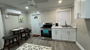 Una cocina moderna con armarios blancos, horno empotrado, lavamanos y ventilador de techo.