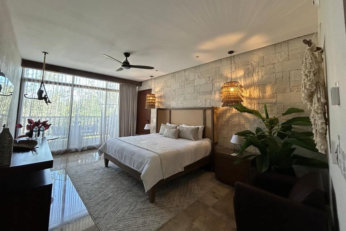 Quarto moderno com uma cama grande, uma escrivaninha e uma janela ampla.
